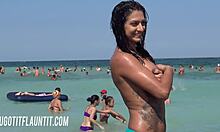 O brunetă cu sânii mari și un corp minunat își arată bronzul pe o plajă