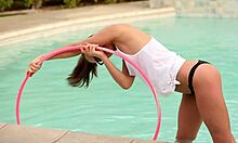 Namorada adolescente com rabo de cavalo usando óculos posando com um aro de hula na piscina