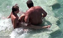 Hyvännäköinen brunette varjoissa osoittaa hänen alaston elin nudisti rannalla