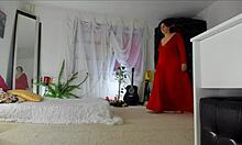 Sensuel moden Sonias hjemmevideo viser sine drillende stillinger i en lang rød kjole, der afslører hendes behårede opskørt, ben, fødder og hofter, med naturlige bryster