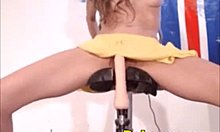 Een jonge vrouw gebruikt een dildo op een fiets voor sensuele bevrediging